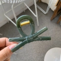 Close-up of a dark green bow hair claw clip with a glossy finish and gold metal spring - Dark Green
