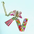Letter V resin keychain with colorful sequins, pink butterfly charm, and soft pink tassel - Letter V