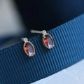Macro shot of oval red garnet earrings with silver beaded edges on blue ribbon - Silver & Red