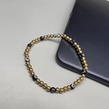 18K gold-plated beaded elastic bracelet with blue evil eye charms on grey desk - Black Eye - Gold