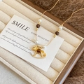 Golden rocking horse necklace with pearls and tiger eye stones on jewelry tray - Gold-Coffee-White