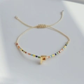 Detail eines böhmischen Miyuki-Perlenarmbands mit verstellbarem Knoten und goldenem Buchstaben F - Buchstabe F