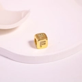Detailed macro view of gold square bead with letter F and micro-set zircons for DIY jewelry - Letter F