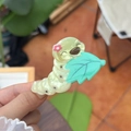 Primer plano de una bonita pinza para el pelo de oruga en acrílico verde claro en la mano - Pinza de Oruga Verde