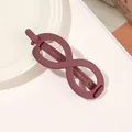 Detail of infinity-shaped matte purple hair claw clip displayed on a white ceramic plate - Infinity - Wine Red