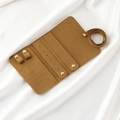 Detail view of brown microfiber jewelry roll with metal snaps on white silk - Microfiber / Brown Microfiber