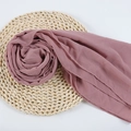 Elegant dusty rose chiffon hijab scarf neatly displayed on a rustic woven straw mat - 82