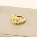 Macro detail of golden twisted rope ring showing polished metallic texture and intertwined layers - US 6