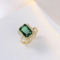 Elegant gold titanium steel ring with emerald green gemstone and zircon halo on white background - Emerald Green Ring
