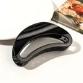 Close-up of a large glossy black hair claw clip for long hair on a decorative white dish - 12cm Moon - Shiny Black