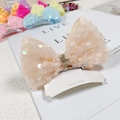 Macro view of peach sequin mermaid bow hair clip with metal alligator grip and tag - Sequin Snow Bud