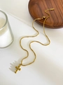 Dettaglio della collana in acciaio al titanio dorato con catena a sfere e pendente a croce - Croce di perline 3D