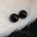 Vista macro de pendientes de perla negra brillante sobre fondo de piel sintética blanca - Negro