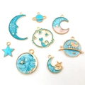 Vue détaillée de 8 pendentifs célestes en émail doré avec motifs lune étoiles et planètes - Série Bleu Lac