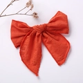 Close-up of orange floral embroidered bow clip with delicate stitching on fabric - Red