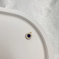 Dettaglio di un ciondolo d'oro con gemma blu circondata da pietre bianche - Tipo A: Tondo Oro Zircone Blu