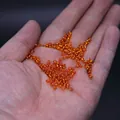 Transparent orange glass seed beads for DIY jewelry making held in a palm for scale - 3mm / 15g / Orange