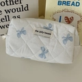 Close-up of quilted cosmetic bag featuring blue bow patterns and The Jolly House label - Pencil Case / Blue Bow