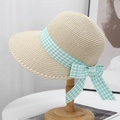 Détail d'un chapeau de paille d'été avec ruban pied-de-poule sur support bois - Beige