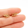Minimalistische goldene Herz-Pfeil-Ohrstecker aus Edelstahl an den Fingern gezeigt - Gold