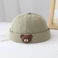 Detail of pea green beanies for boys featuring a brown cartoon bear patch on cotton twill - Toddler One Size / Light Green