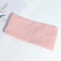 Pink ribbed knitted headband with cross-knot design on a minimalist white background - Pink