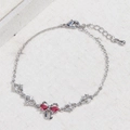 Dettaglio macro del bracciale a fiocco argentato con zirconi rossi a cuore - Oro Bianco