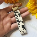 Vue détaillée d'un porte-clés en cuir véritable imprimé vache avec fermoir doré - Imprimé Vache (3)