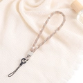 Detailed close-up of champagne luxury rhinestone chain lanyard with metal clasp on fabric - Champagne + White