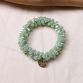 Close-up of light green beaded hair tie with gold brand tag on silk background - Jelly Green