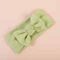 Soft light green ribbed knit baby headband with a decorative bow on pink background - Fruit Green