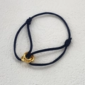 Detail of adjustable black woven cord bracelet with three interlocking golden rings - All Gold Rings And Black Rope