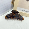 Macro detail of a large tortoiseshell claw clip on a textured fabric surface - Tortoiseshell 2