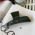 Detail of dark green glossy hair claw clip placed on a white magazine with glass decor - Jelly Dark Green