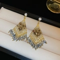 Macro shot of rhombus tassel earrings with amber crystals on a beige leather display - Gold Blue (15#)