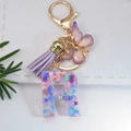 Letter R resin keychain with purple tassel and snowflake sequins on white leather base - Letter R