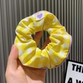 Yellow plaid hair scrunchie with purple trim and heart tag held by hand - Large Grid / Yellow