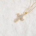 Minimalist gold cross necklace with marquise zircon crystals on a white stone background - White