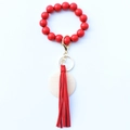 Détail du porte-clés bracelet en perles rouges avec pompon en cuir et disque en bois - Rouge