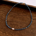 Detail of freshwater pearl necklace with blue faceted beads and gold spacers on wood - Necklace / Blue