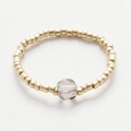 Macro shot of handmade beaded ring with gold round beads and a clear raw crystal stone - Gold & Clear