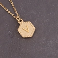 Detail of a gold hexagonal pendant featuring an embossed letter V on a cross chain - Letter V (22#V)