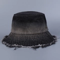 Detail eines Denim Anglerhuts mit Farbverlauf, Fransen am Rand und einem kleinen Metallemblem - Schwarz
