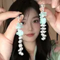 Detailed view of light blue acrylic flower tassel earrings with silver chains on model - Blue Gradient Petal Style (10#)