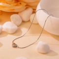 Collier cœur argenté élégant sur un bol blanc avec fleurs et galets blancs - Collier avec pendentif cœur argenté