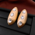 Vintage matte gold oval earrings with three clear crystals on black textured display - Gold Transparent Brushed Style