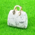 Miniature white marble crystal handbag pendant with golden metal handle on green moss - Howlite