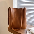 Detailansicht der braunen Leder-Eimertasche mit Nähten und verstellbarem Riemen auf Holz - Braun