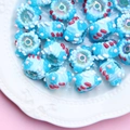 Macro shot of blue cylinder glass beads with red and white hand-painted dots on a plate - Transparent Blue Bead Blue Cream Blue Flower