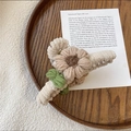 Close-up of plush knitted flower hair claw on a wooden tray with a vintage vibe - Khaki Floral